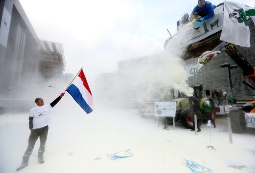 A milk producer waves a Dutch flag as farmers spray powdered milk to protest against dairy market overcapacity in Brussels