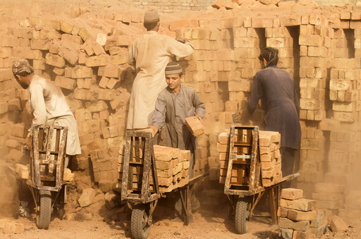 Laborers move baked bricks from an oven at a kiln on outskirts of Peshawar