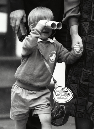 Prince Harry looks through a pair of toy binoculars he made on his first day at kindergarten