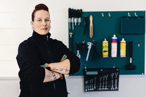 Portrait of confident female mechanic standing arms crossed in auto repair shop
