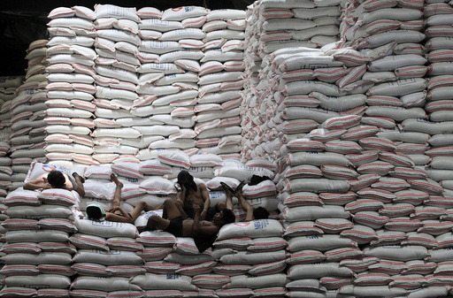 Workers take a break atop sacks of rice piled inside a warehouse of National Food Authority (NFA) in Taguig city