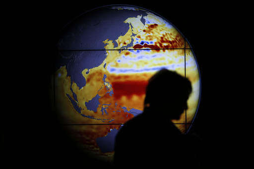 A woman walks past a map showing the elevation of the sea in the last 22 years during the World Climate Change Conference 2015 at Le Bourget
