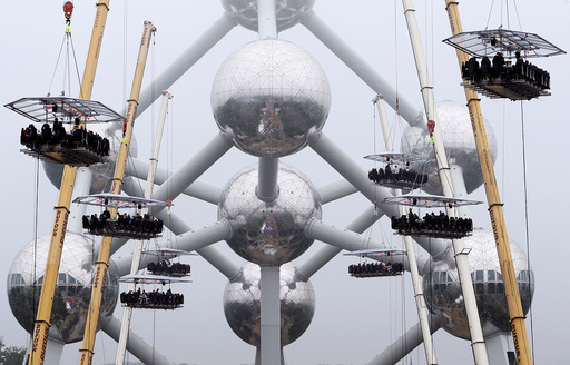 Guests sit at tables suspended from cranes at a height of 40 metres in front of the Atomium, as part of the 10th anniversary of the event known as Dinner in the Sky, in Brussels