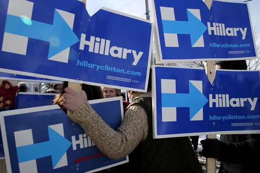 U.S. Democratic presidential candidate Hillary Clinton greets campaign volunteers holding signs while going to door-to-door to greet voters in a neighborhood in Manchester