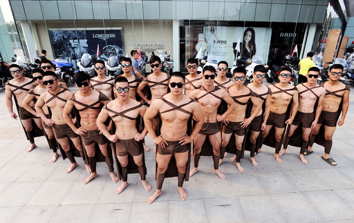 Male fitness instructors and students dressed in costumes of Spartan warriors pose during the one-year anniversary for Juicedaily, in front of a shopping mall in Xuzhou