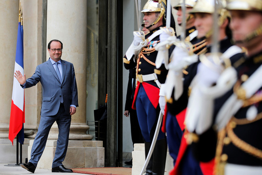 French President Francois Hollande waves as he accompanies a guest after a meeting at the Elysee Palace in Paris