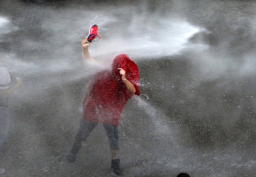 A Lebanese protester is sprayed with water during a protest against corruption and rubbish collection problems near the government palace in Beirut