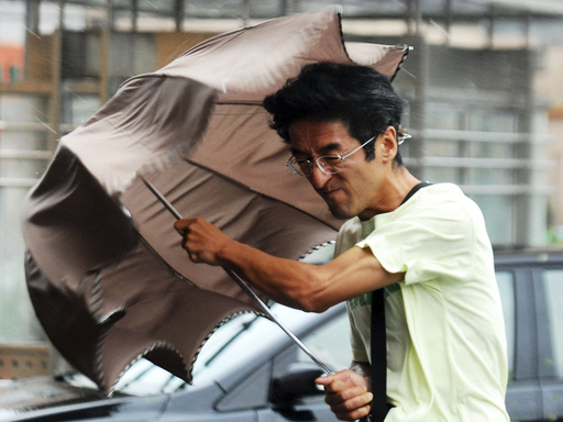 A man holds onto his umbrella against strong wind and heavy rainfalls on a street as Typhoon Haikui hit Shanghai