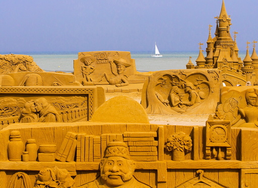 A sailing boat is seen behind sand sculptures during the Sand Sculpture Festival Frozen Summer Fun in Ostend