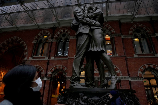 En kvinne går forbi statuen utenfor togstasjonen St. Pancras i London. Storbritannia var et av landene som opplevde omikron-bølgen først. Viruset viste seg å smitte lett, og overtok for deltavarianten, som trolig gir mer alvorlig sykdom. Foto: AP Photo/Matt Dunham/NTB