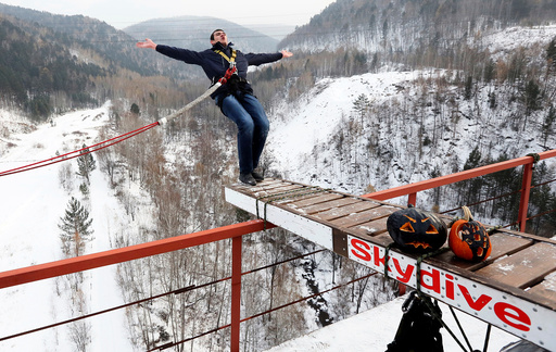 Member of Exit Point amateur rope-jumping group jumps from water pipe bridge to mark end of group's jumping season and recent Halloween festivities outside Krasnoyarsk