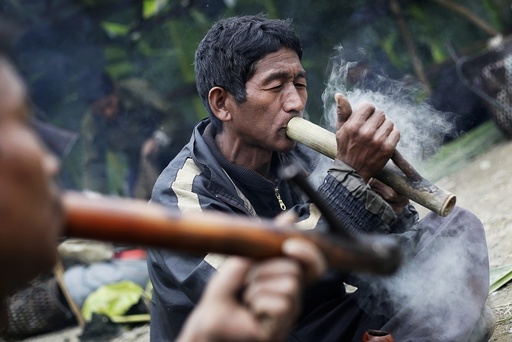 Men smoke opium from traditional pipes made out of bamboo at a hunting base camp in an opium field during a hunting trip between Donhe and Lahe township in the Naga Self-Administered Zone