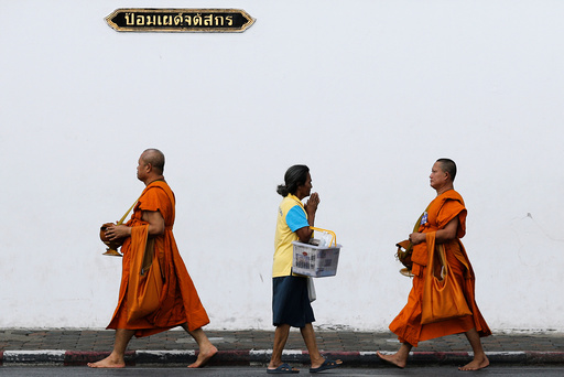 A woman greets Buddhist monks as they arrive for a ceremony at the Grand Palace to commemorate Thailand's King Bhumibol Adulyadej's 70th anniversary on the throne