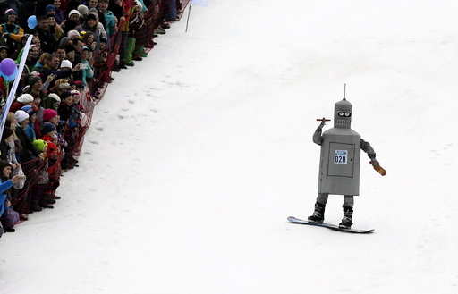 Spectators watch a snowboarder in a fancy costume, slides down before an attempt to cross a pool of water at the foot of a ski slope at the Bobrovy Log ski resort on the suburbs of the Siberian city of Krasnoyarsk