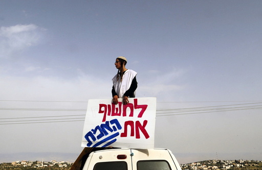 An Israeli right-wing activist takes part in a protest calling for the release of suspected Jewish attackers outside the West Bank village of Duma near Nablus