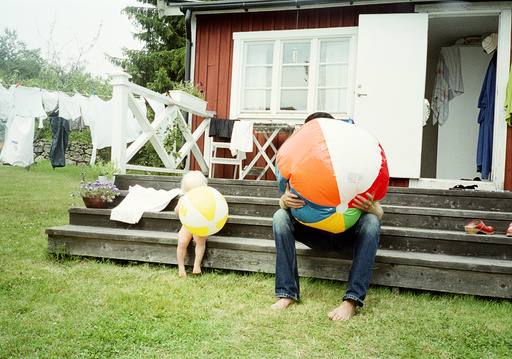 Fahter and daughter inflating beach balls, Blekinge, Sweden.