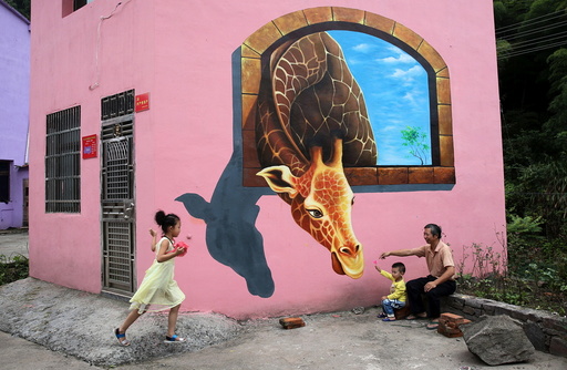 Tourists play in front of3D painting on wall of house in Luoyuan village, Jinhua