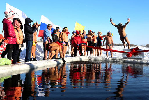 A winter swimmer jumps into icy water to celebrate with other members the establishment of a winter swimming club in Heihe