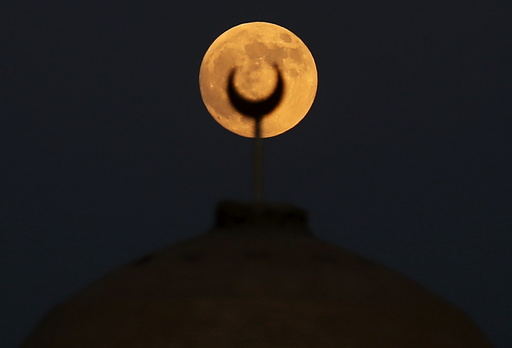 A supermoon, the last of this year's supermoons, rises over a minaret of a mosque in Wadi El-Rayan Lake at the desert of Al Fayoum Governorate, south west of Cairo