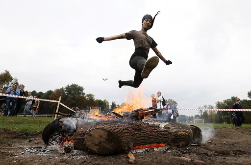Woman jumps over the fire as she takes part in an extreme run competition in Zhodino