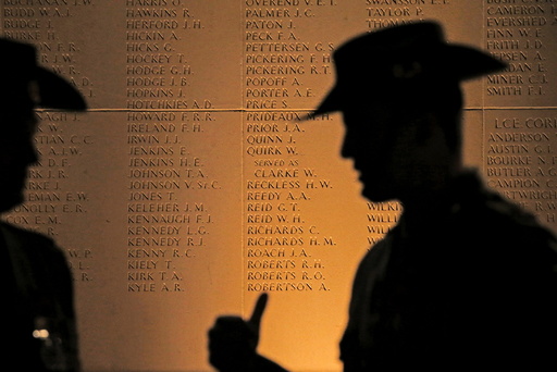 Two Australian soldiers cast shadows on a monument for soldiers during the dawn service to mark the ANZAC commemoration ceremony at the Australian National Memorial in Villers-Bretonneux