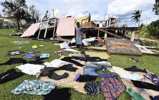 Local resident stands near clothes laid out to dry near damaged home in Port Vila