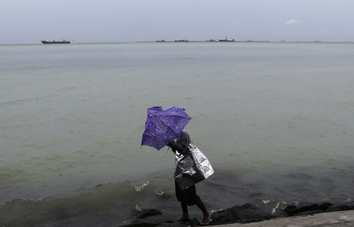 Wind brought by Tropical storm Rumbia blows a man's umbrella while walking along a seawall in Roxas Boulevard in Manila