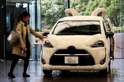A woman touches Toyota's vehicle decorated as shape of dog at its headquarters in Tokyo