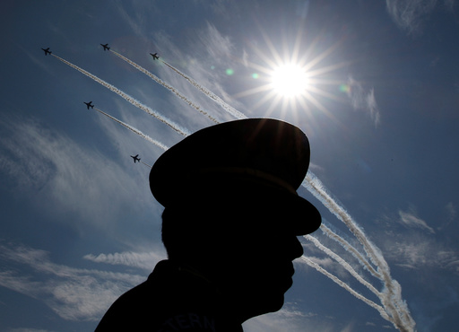 Japanese Self-Defence Forces' (SDF) official is silhouetted while flights performs air show during the annual SDF ceremony at Asaka Base