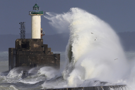 Waves crash against a lighthouse as the wind blows at around 100 kph (62 mph), in Boulogne-sur-Mer
