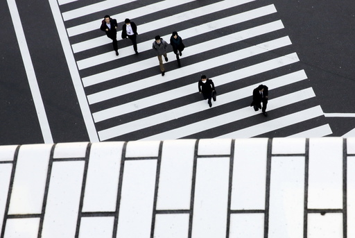 People cross a street in a business district in Tokyo
