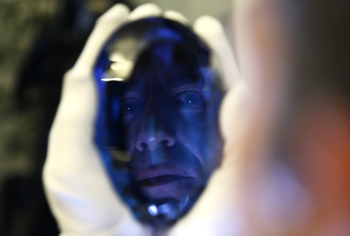 Philanthropist Maurice Ostro is reflected in his Ostro stone, the largest known blue topaz stone, as he holds it for media at the Natural History Museum in London