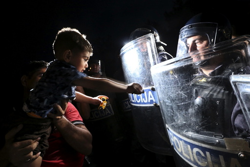 A migrant holds a child in front of Slovenian police at the boarder from Croatia to Slovenia in Harmica