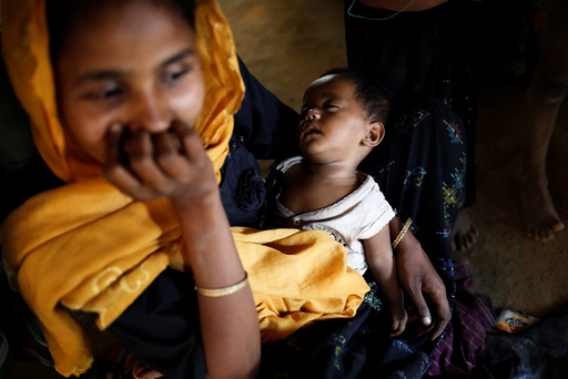 A Rohingya child sleeps on mother's lap inside their house, at Balukhali Makeshift Refugee Camp