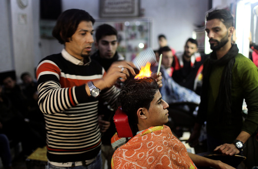 Palestinian barber uses fire to straighten the hair of a customer in Rafah in the southern Gaza Strip