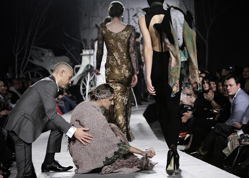 A model is helped by a spectator after she fell while presenting a creation by Georgian designer Irakli Nasidze during Georgian Fashion Week in Tbilisi