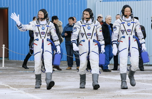 Members of the main crew of the expedition to the International Space Station (ISS), walk to report to members of the State Committee prior the launch of Soyuz TMA-19M space ship at the Russian leased Baikonur cosmodrome, Kazakhstan