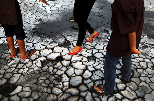 Tourists walk on dried mud at the Lapindo mud field in Sidoarjo