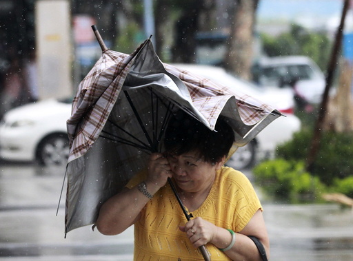 A woman holds her umbrella while walking against strong winds as Typhoon Soudelor hits Taipei