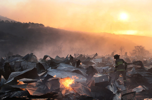A firefighter removes the remains of a burned house on a hill, where more than 100 homes were burned due to forest fire but there have been no reports of death, local authorities said in Valparaiso, Chile