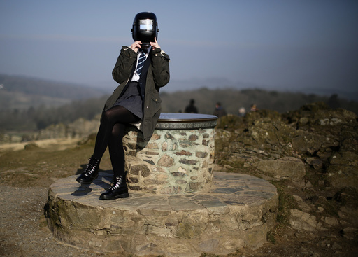 A girl uses a welding mask to view a partial solar eclipse from Bradgate Park in Newtown Linford