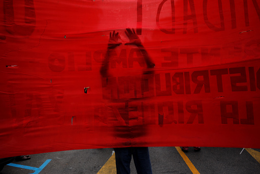 A supporter of the Communist party uses a scissors to make holes on a banner as he takes part in a May Day rally in Malaga