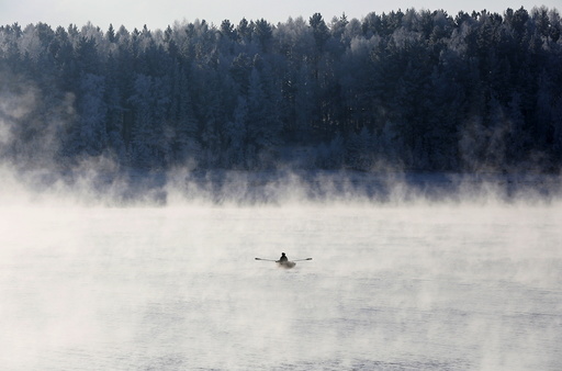 A man rows a boat through a frosty fog along the Yenisei River at air temperature some minus 20 degrees Celsius in the Taiga district outside the Siberian city of Krasnoyarsk, Russia