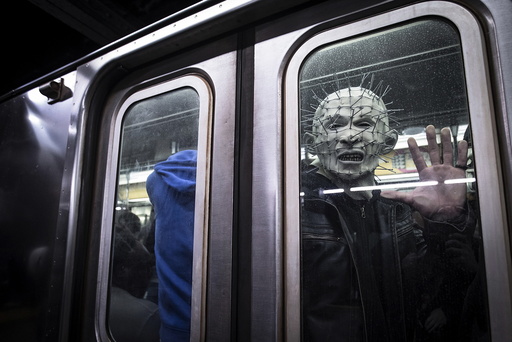 A man dressed up as Pinhead from the Hellraiser series poses for a photo as his subway train pulls away at Times Square station in Manhattan
