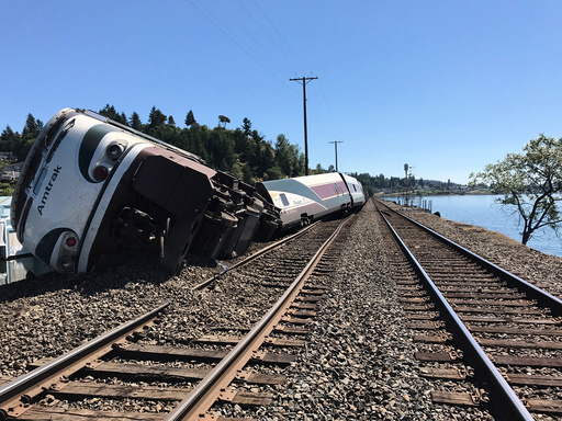 A derailed Amtrak passenger train lies on its side before the Chambers Bay Bridge on Puget Sound in Steilacoom