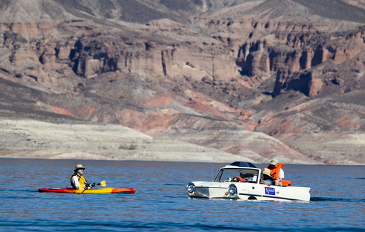 A kayaker looks over a 1965 Amphicar, driven by Dean Baker of Lake Havasu, Arizona, during the first Las Vegas Amphicar Swim-in at Lake Mead near Las Vegas