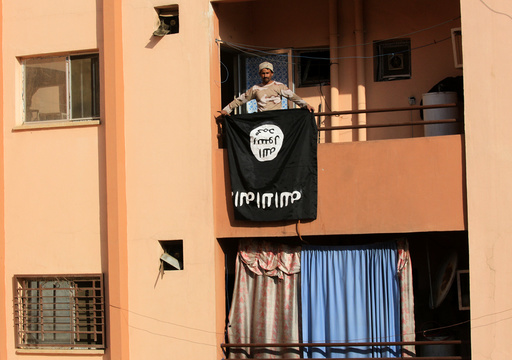 An Iraqi soldier holds an Islamic State flag from a building, during a battle with Islamic State militants in Al-shuqaq neighbourhood north of Mosul