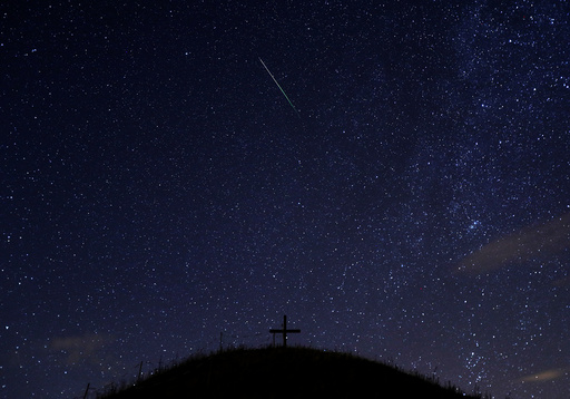 A meteor streaks past stars in the night sky above Leeberg hill during the Perseid meteor shower in Grossmugl