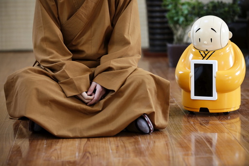 Robot Xian'er is placed next to Master Xianfan while Xianfan has an interview with Reuters at Longquan Buddhist temple on the outskirts of Beijing
