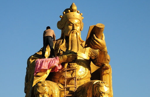 A worker paints as he repairs a bronze statue of a Guan Yu, a Chinese historical figure, in Nanyang